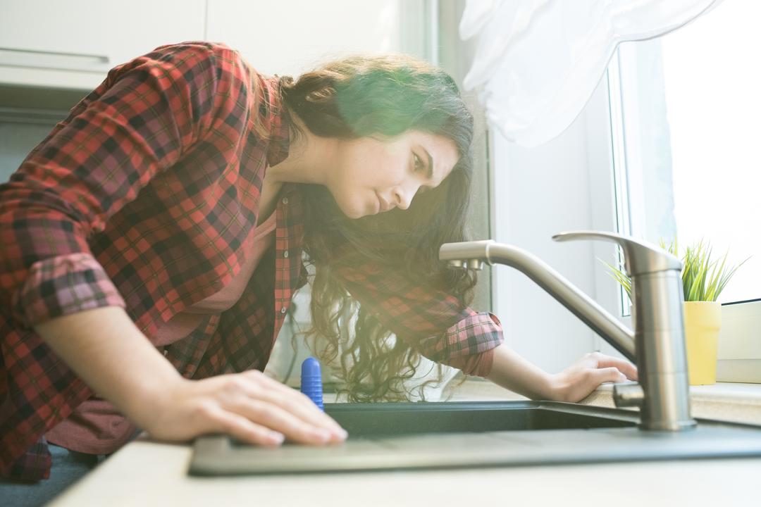 Woman inspecting her sink and drain.